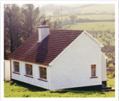 A photo of a white cottage on a hill